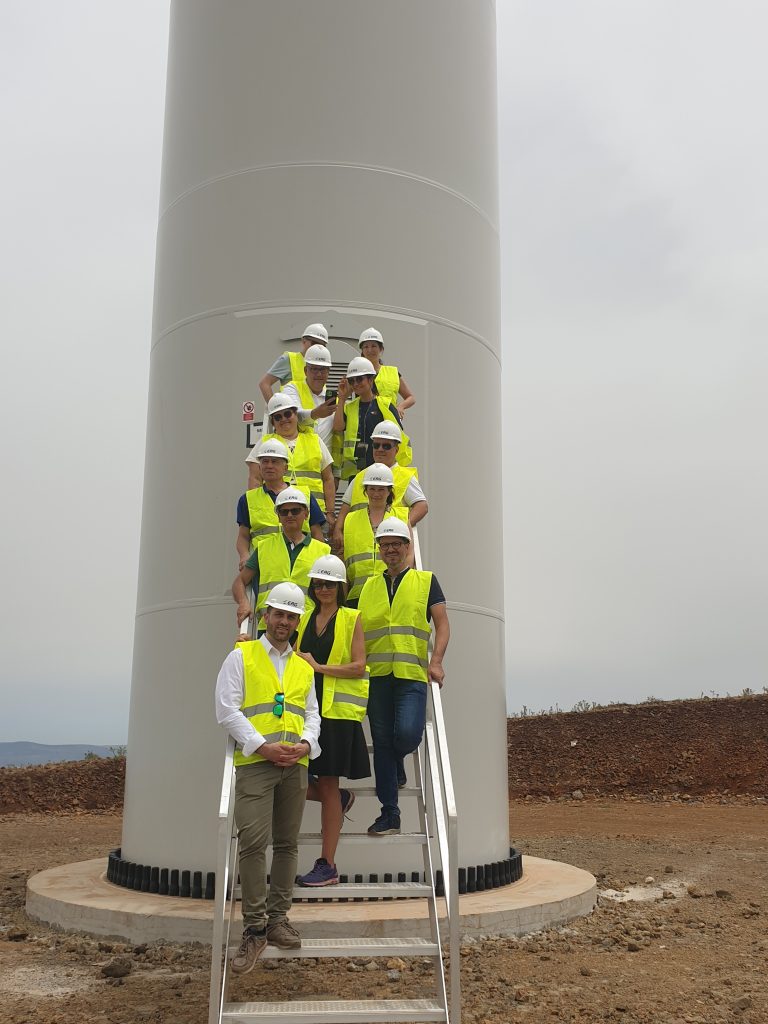 A group of people in safety vests standing on stairs outside of a windmill
Description automatically generated
